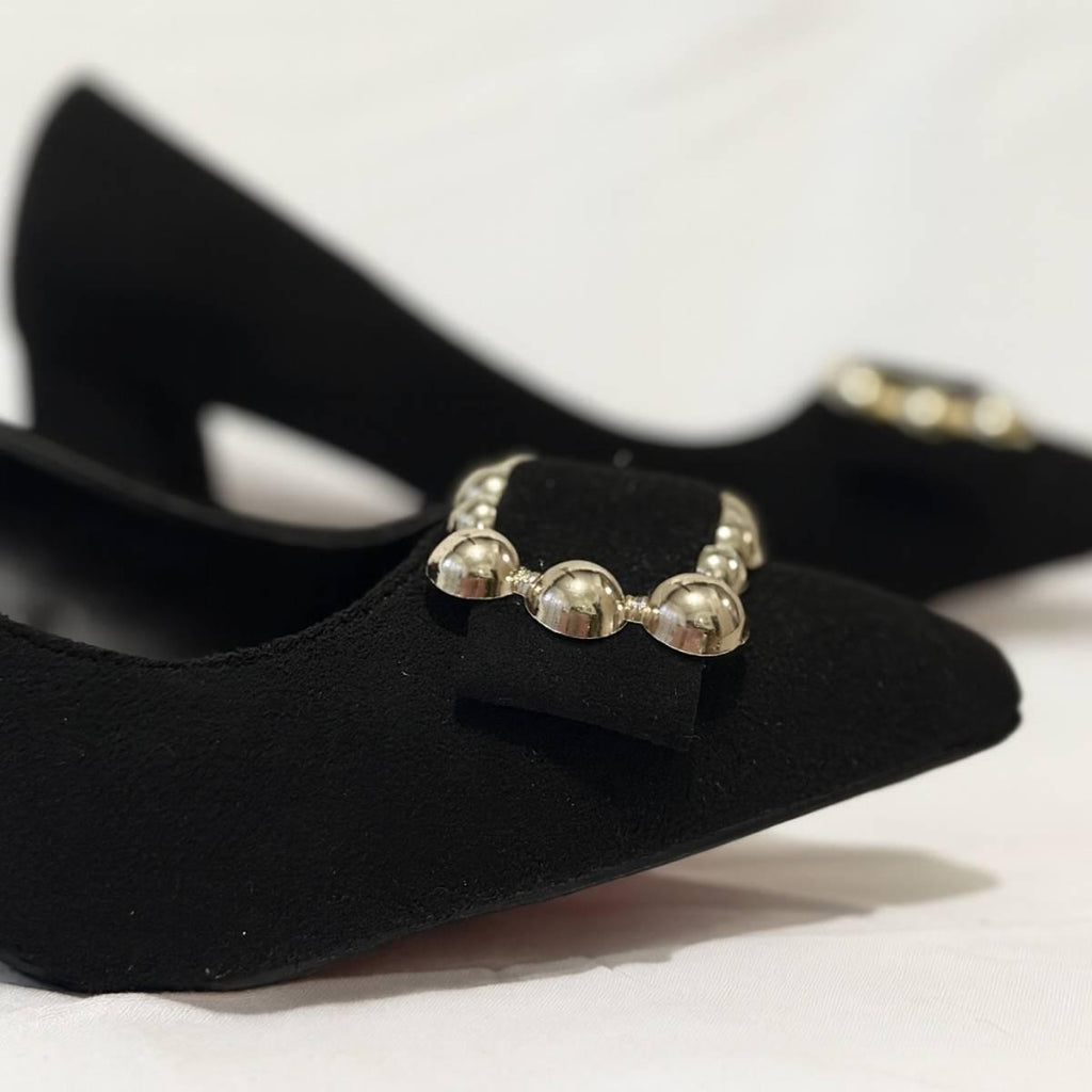 Close-up of Amara Noir Chain Block Heels gold chain detail on black suede upper.