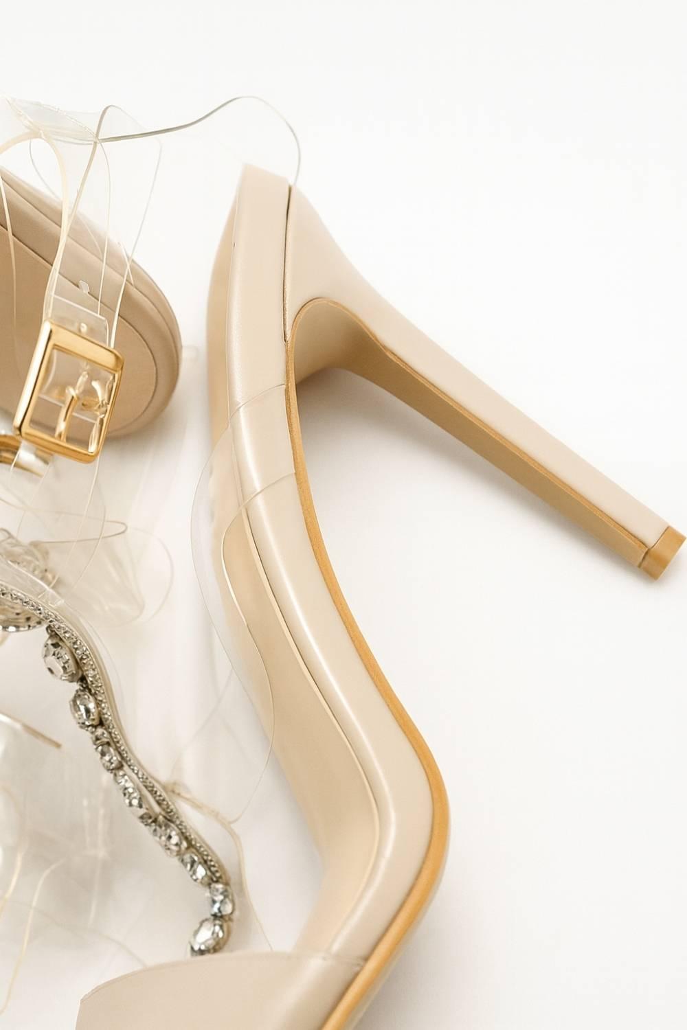 Detail view of Crystal Veil Stiletto Heel focusing on nude base, transparent strap, and gold buckle