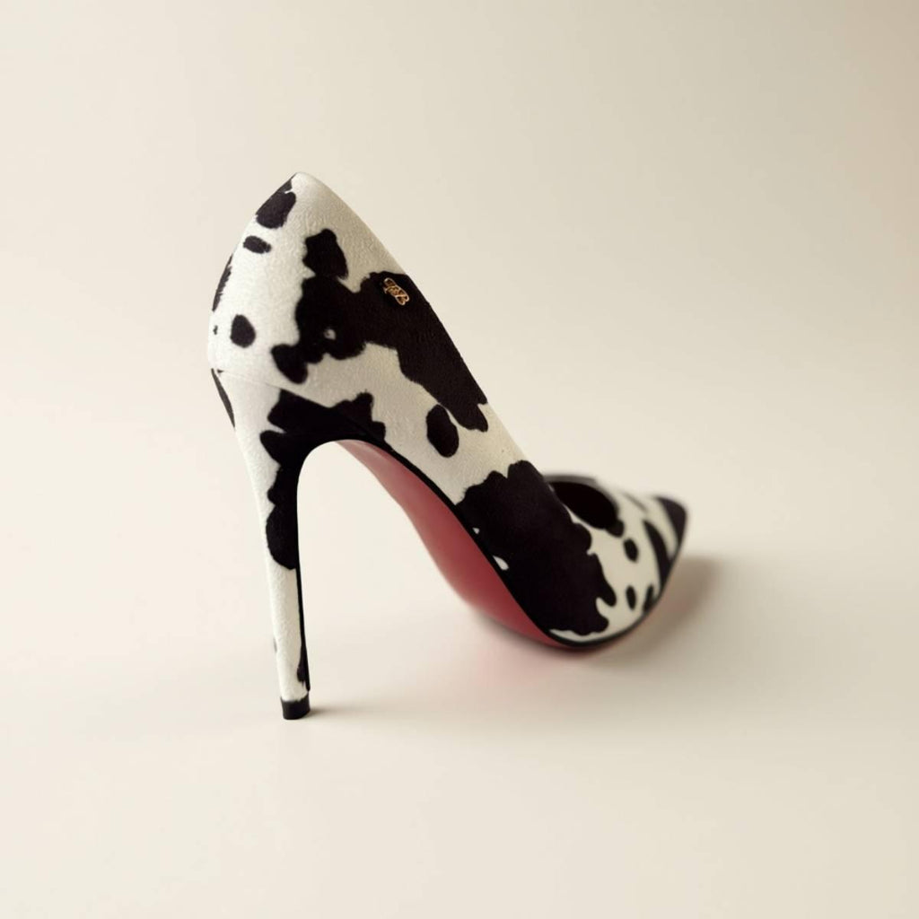 Back angle of Noir Cowhide Stiletto showcasing black-and-white pattern and red sole.