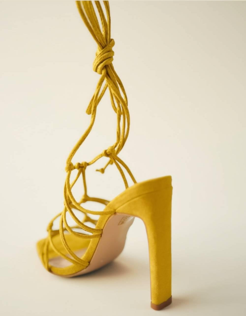 Back angle view of Zuri Mustard Lace Heels showcasing heel shape and tie-up strap design