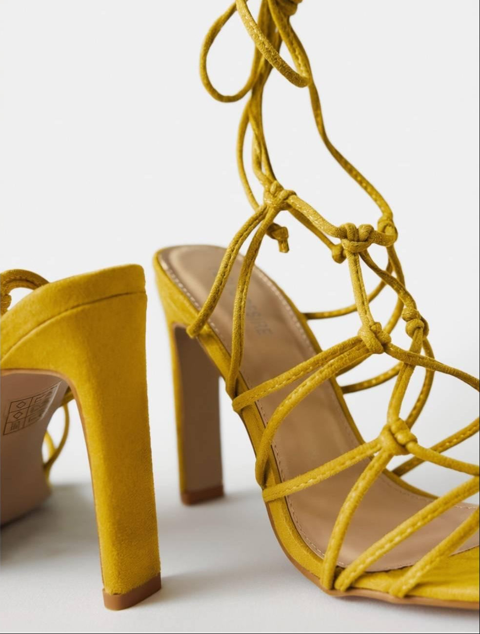 Macro detail of Zuri Mustard Lace Heels highlighting suede finish, knots, and ankle lace texture